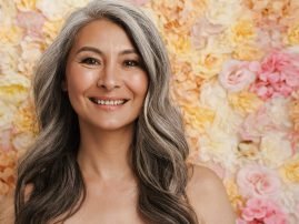 Smiling mature topless woman standing posing over floral wall background